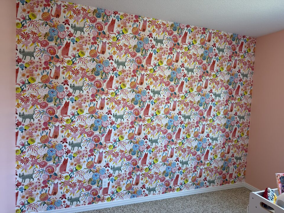 Angled view of a colourful cat and flower wallpaper accent wall with pattern matched seams in an Auburn Bay Calgary kids room