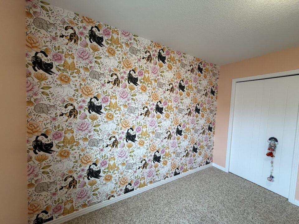 Cats and roses botanical wallpaper meeting crisp white baseboards and closet trim in an Auburn Bay Calgary bedroom