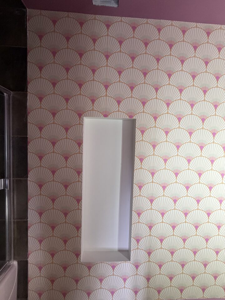 Art deco fan wallpaper around a recessed white niche above dark tile in a Canmore bathroom