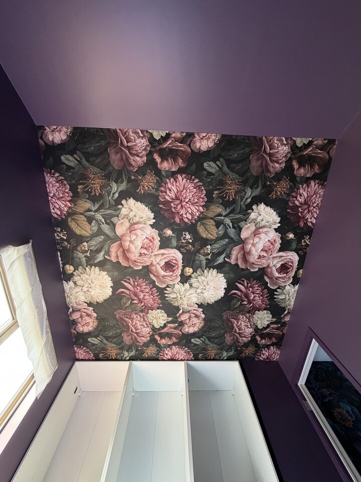 Dark floral mural wallpaper beside white built-in shelving in a plum Canmore dressing room