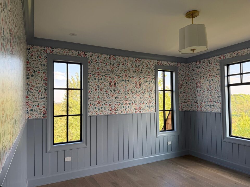 Wildflower wallpaper above blue shiplap wainscoting wrapping around a corner and two windows in an Elbow Valley new build near Calgary