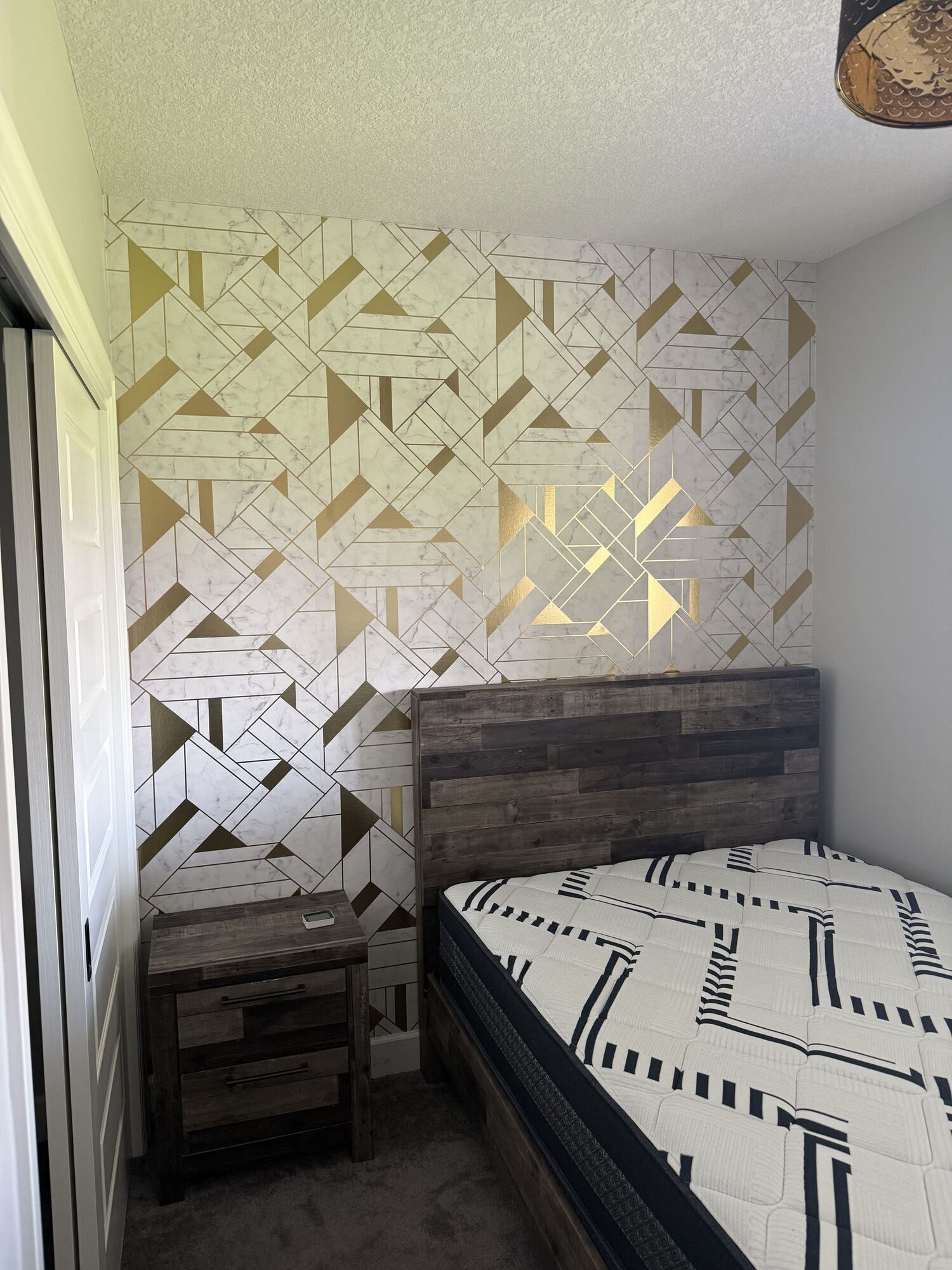 Marble-effect wallpaper with metallic gold geometric inlay on a bedroom feature wall behind the bed, Yorkville, SW Calgary