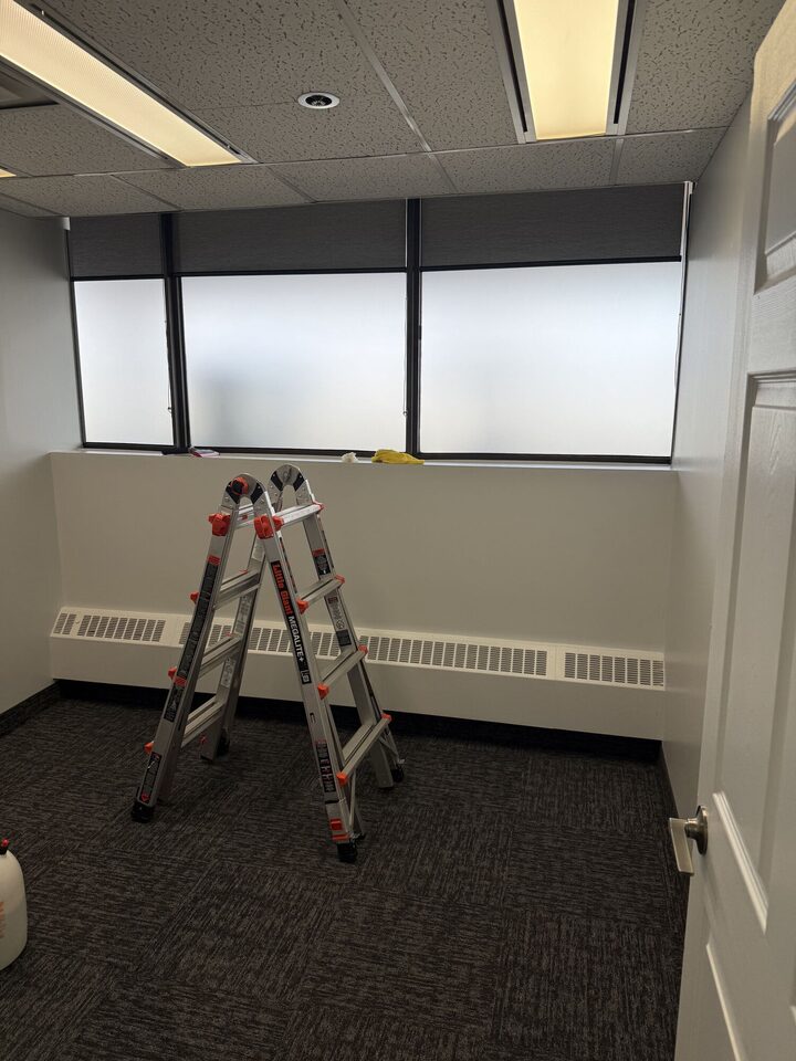 Frosted privacy film installation in progress with a ladder at the full-height window band of a private office, Centre 89, Haysboro, SW Calgary