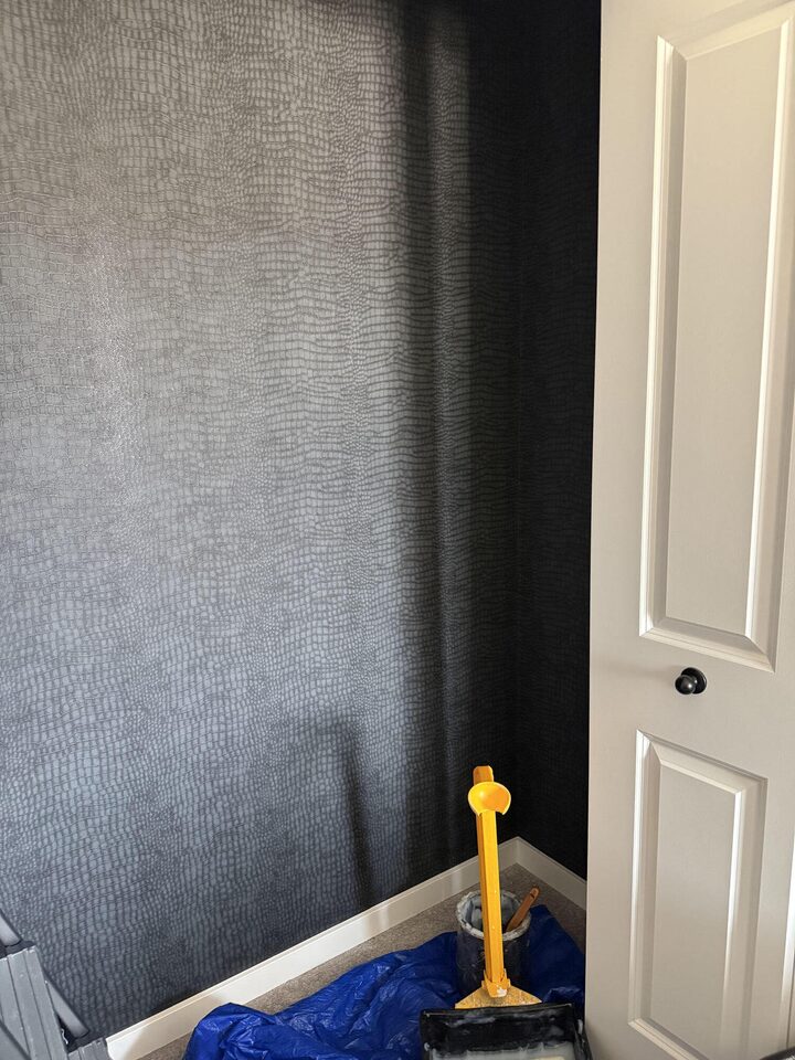 Crocodile-texture wallpaper installation in progress with floor protection and smoothing tools, Heritage Hills, Cochrane