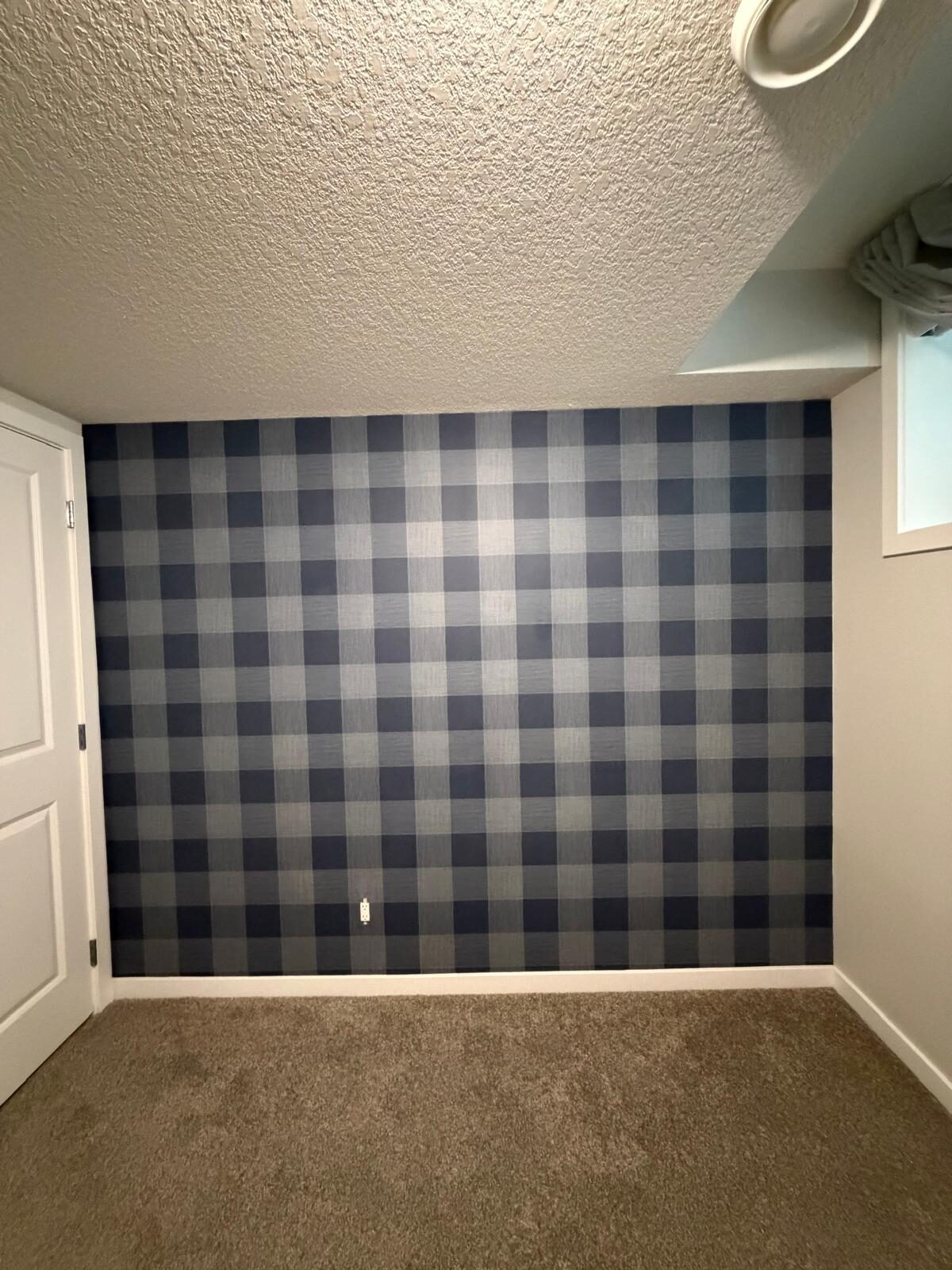 Navy and grey buffalo check wallpaper accent wall installed in a basement bedroom in Legacy, SE Calgary