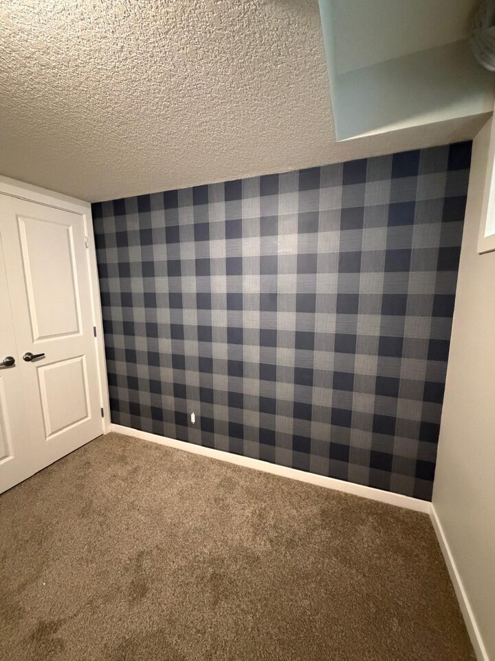 Angled view of a navy buffalo check wallpaper accent wall with crisp pattern alignment in Legacy, Calgary