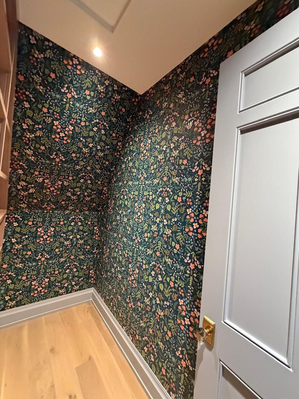 Dark botanical wallpaper pattern-matched around an inside corner of a Calgary walk-in closet