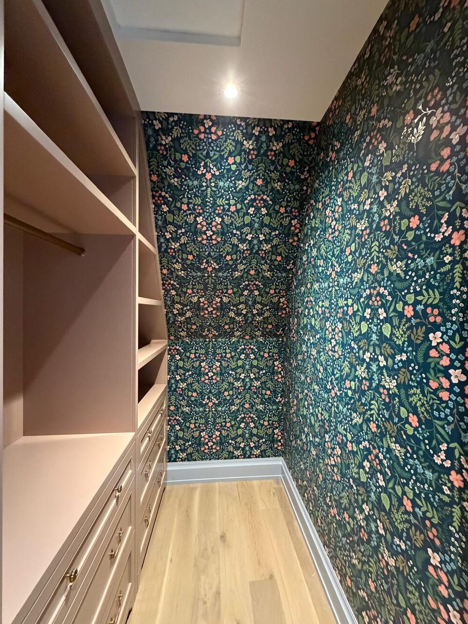 Dark botanical wallpaper feature wall beside custom closet built-ins and drawers in a Springbank Hill dressing room, Calgary