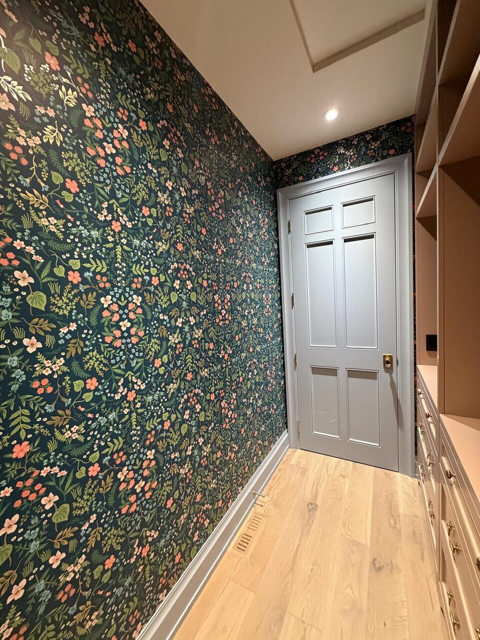 Dark botanical wallpaper carried over the door head of a Springbank Hill walk-in closet, Calgary