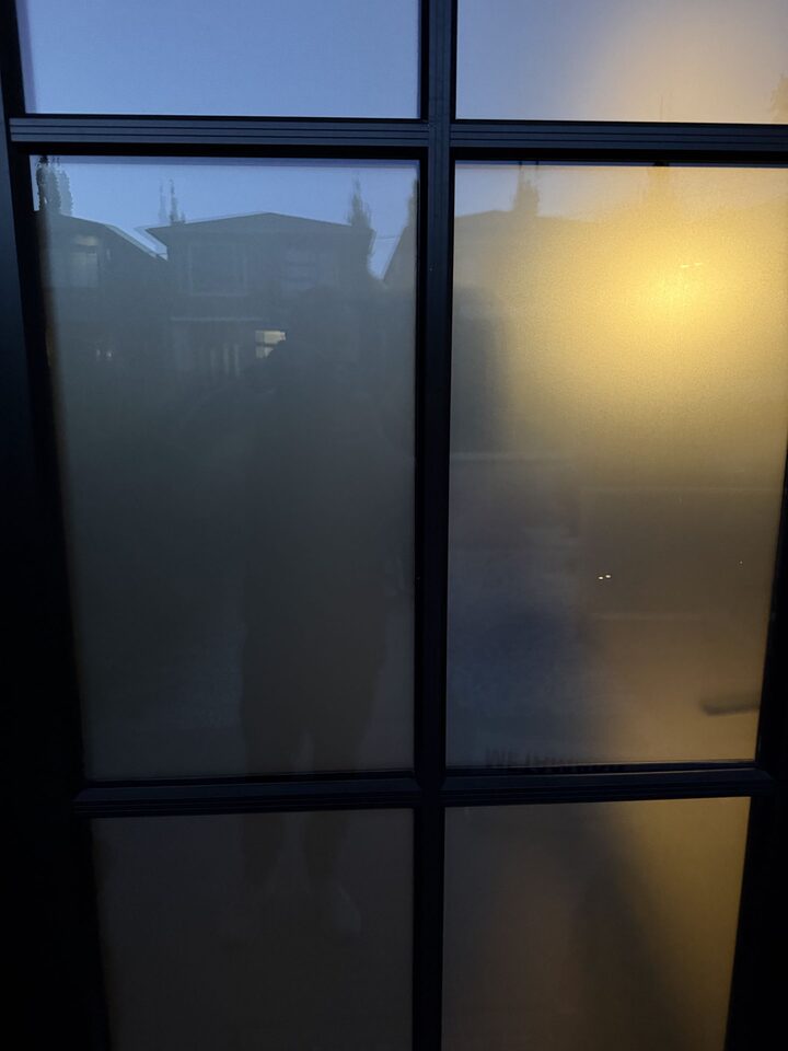 Looking out through the frosted Altadore front door at dusk, street lights and houses reduced to blurred shapes