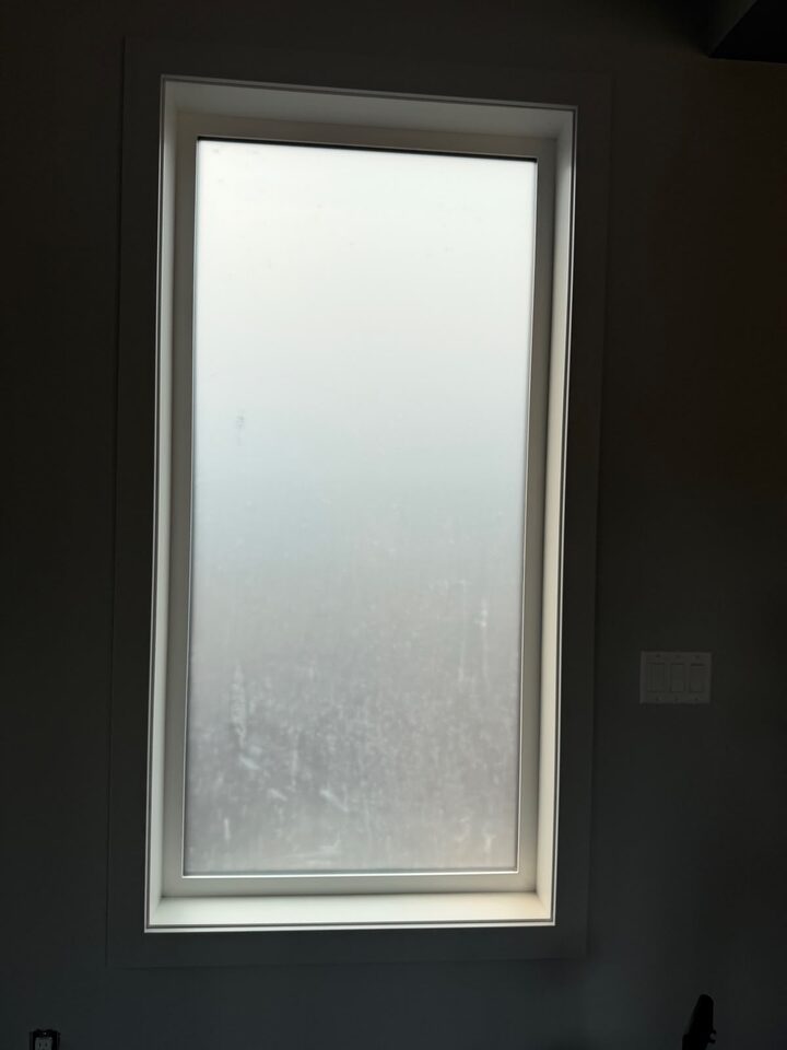 Frosted privacy film on a tall bedroom window letting in daylight while blocking the view, Charleswood NW Calgary new build