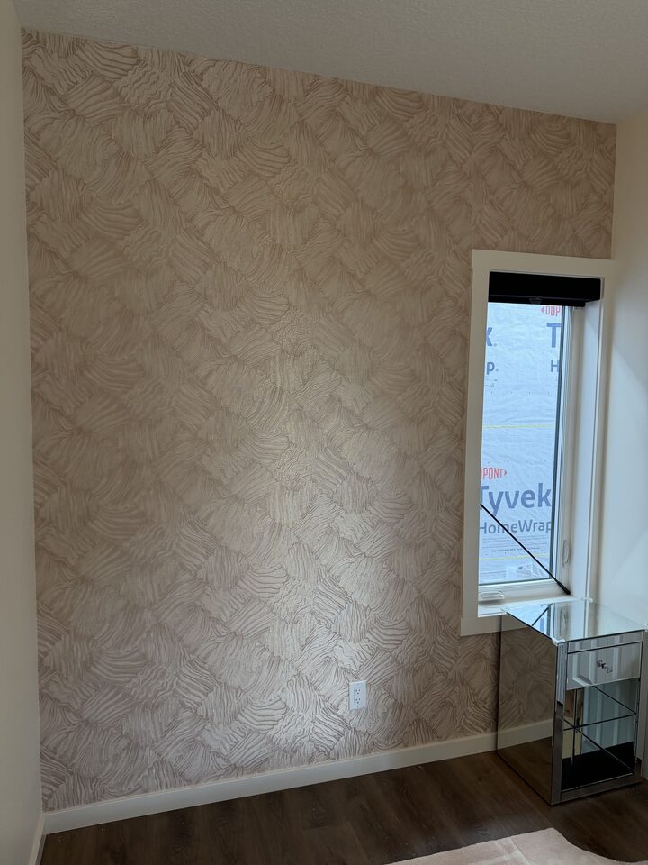 Close view of rose-gold textured wallpaper fitted around window trim in a Cochrane bedroom