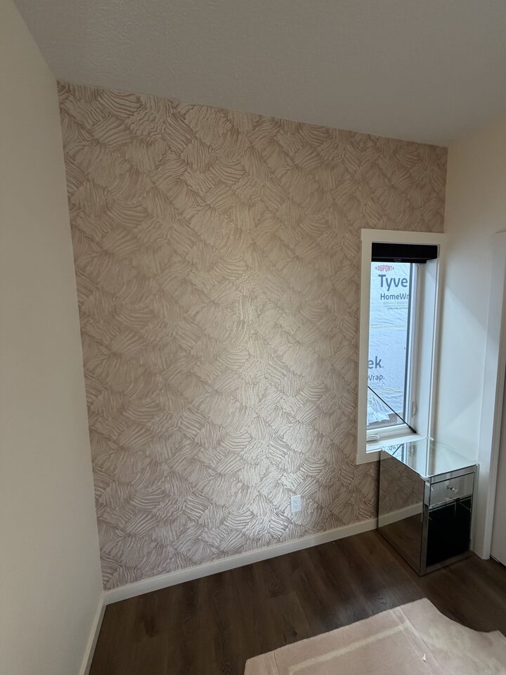 Finished rose-gold textured wallpaper accent wall cut around a narrow window in a Cochrane bedroom