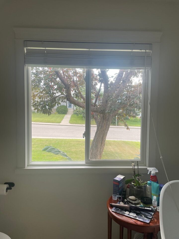 Street-facing bathroom window with clear glass before privacy film, showing a direct sightline to the street in Collingwood, NW Calgary