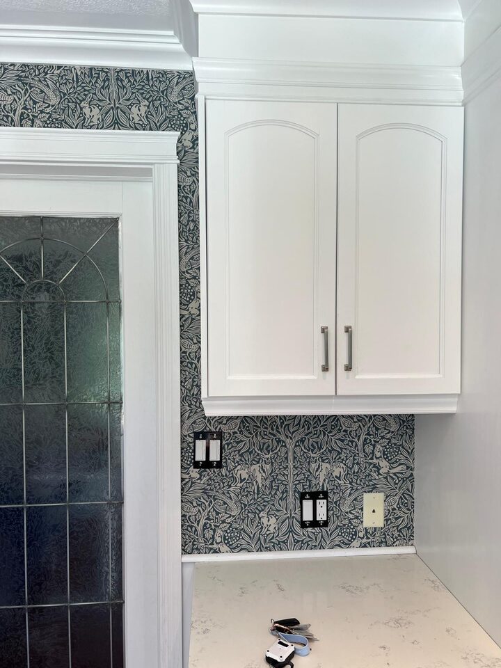 After photo of blue botanical wallpaper installed behind cabinetry and door trim in a Deer Run SE Calgary dining room