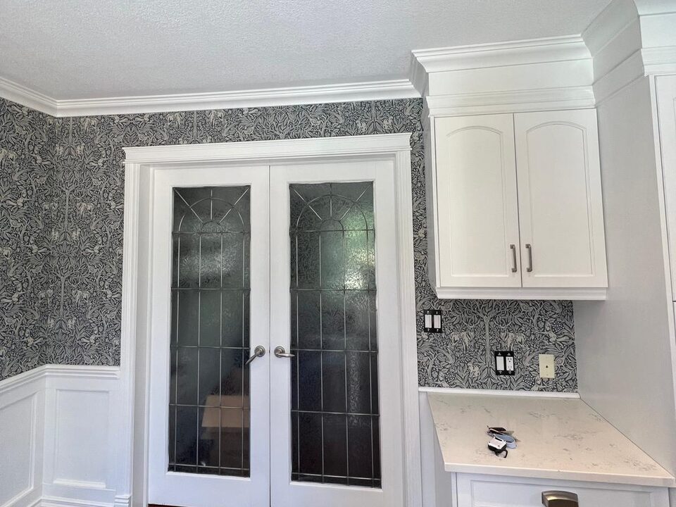 After photo of blue botanical wallpaper installed around double doors and cabinetry in a Deer Run SE Calgary dining room
