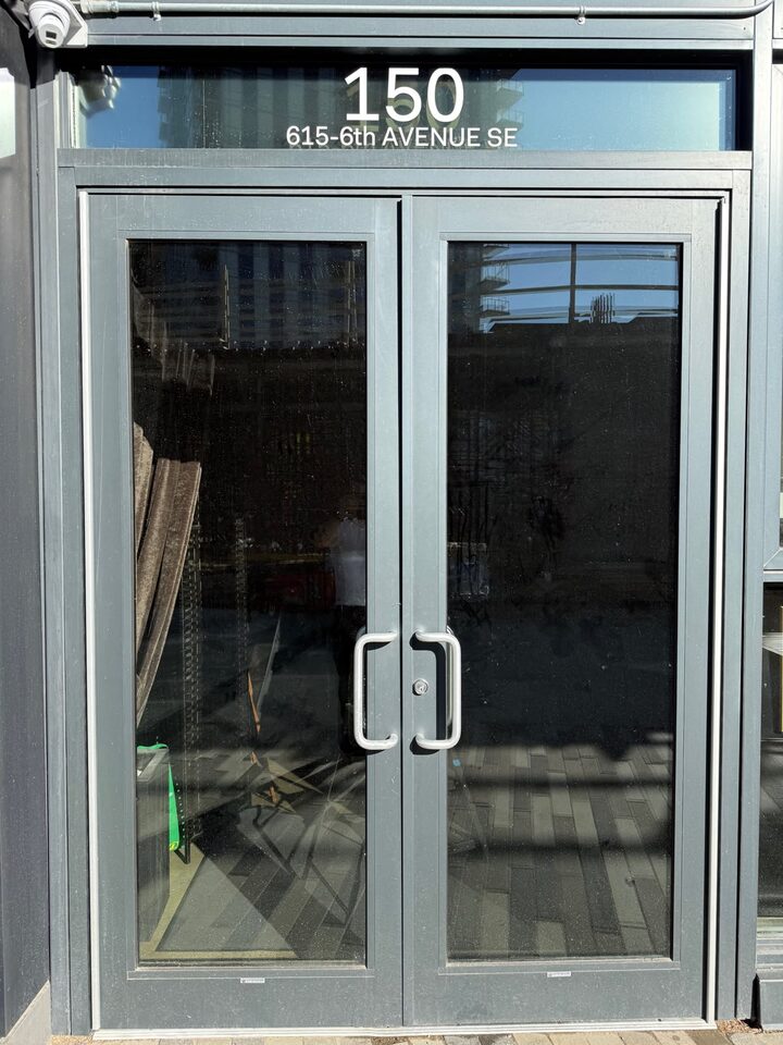 Double glass entry doors with Madico Optivision 45 DA solar film and address lettering on the transom, East Village storefront, Calgary