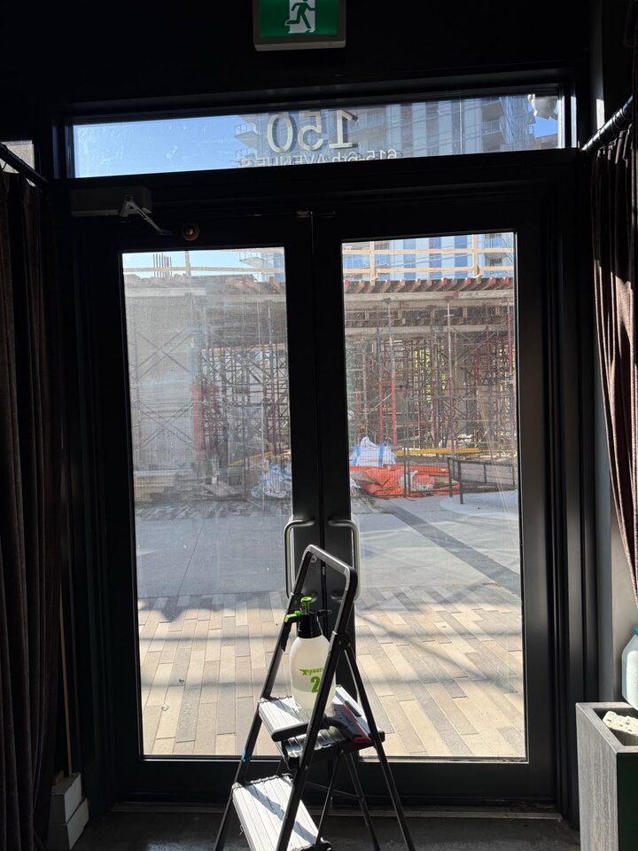 View through solar-filmed entry doors from inside the East Village storefront on installation day, Calgary