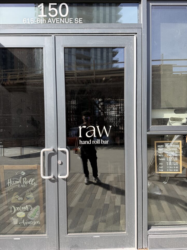Cut-vinyl business-name lettering and address graphics on a filmed glass entry door in East Village, Calgary