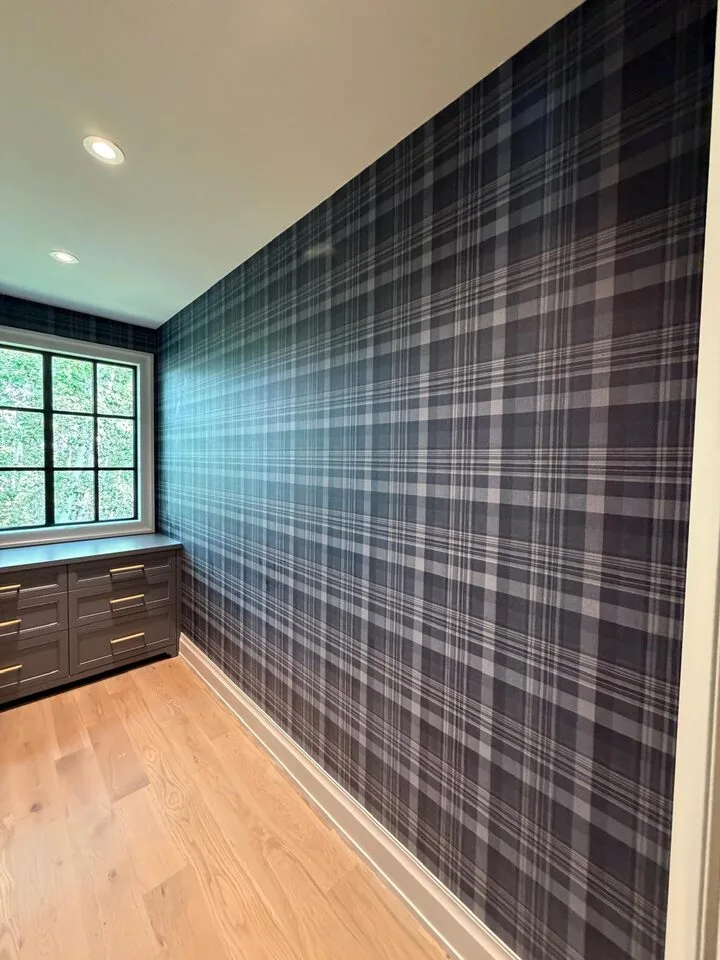 Navy tartan plaid wallpaper pattern-matched across walls and sloped dormer ceilings in an Elbow Valley walk-in closet west of Calgary