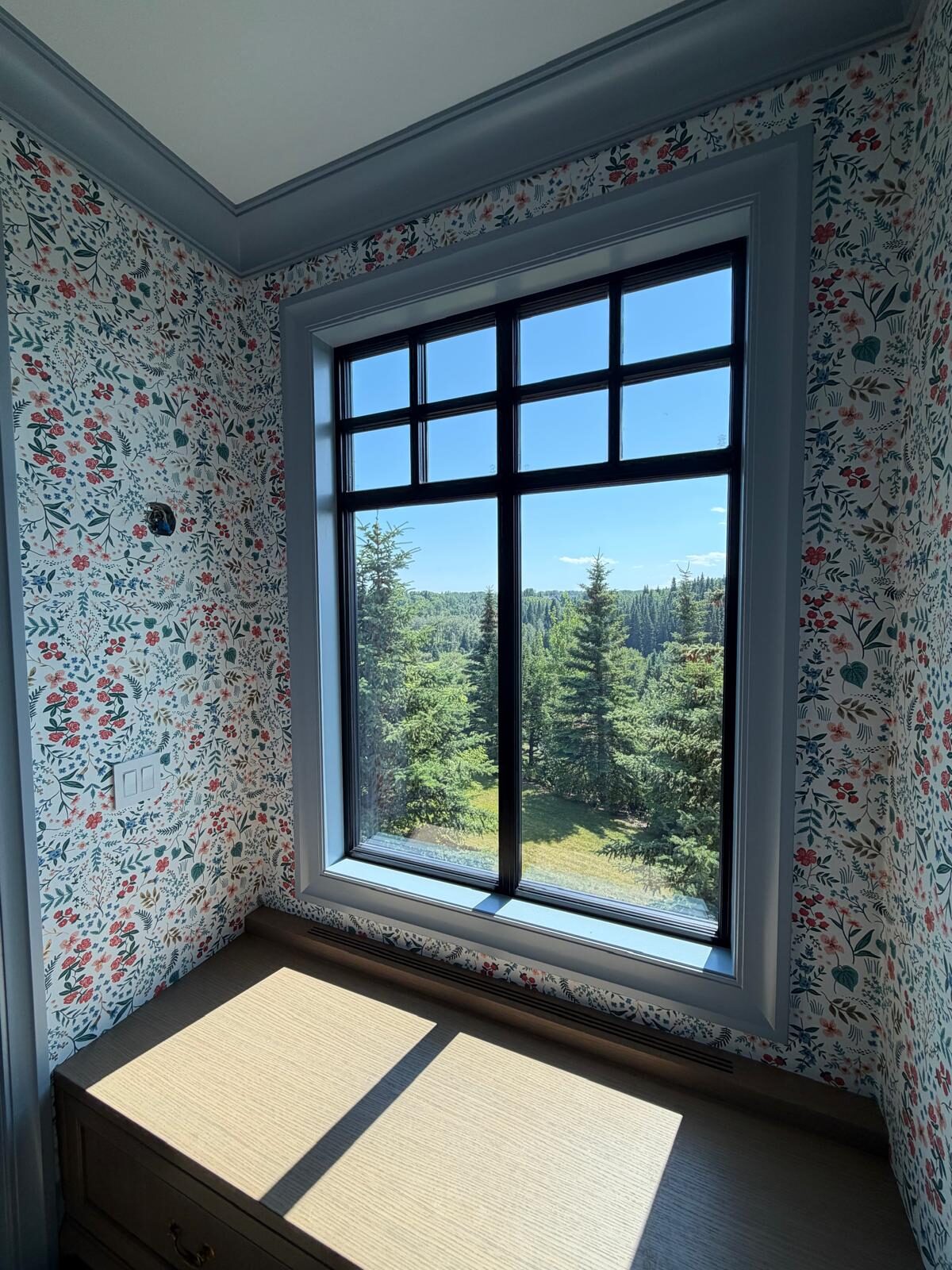 Wildflower botanical wallpaper around a window seat with a forested valley view in an Elbow Valley library nook, west of Calgary