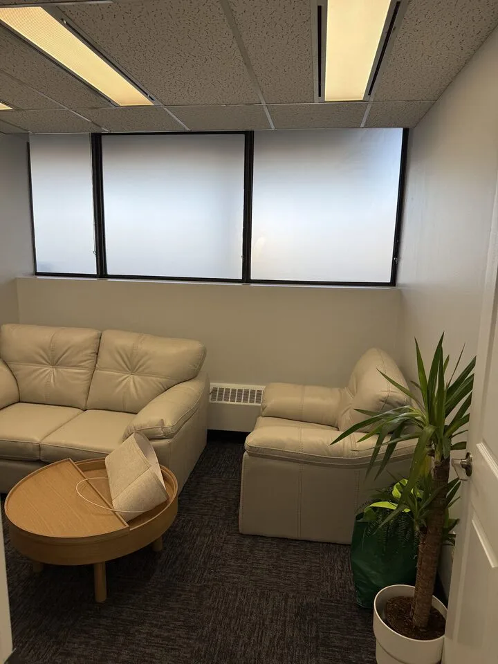 Staff lounge after frosted privacy film, the window wall reading as an even bright panel above leather sofas, Centre 89 office suite, Haysboro, SW Calgary
