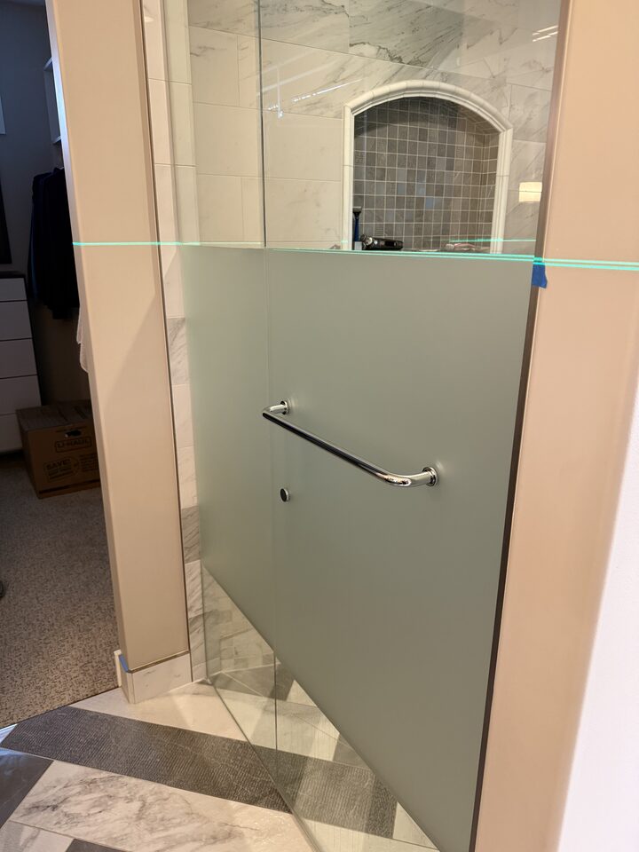 Frosted privacy film on a glass shower door with chrome handle cut in cleanly, Heritage Pointe south of Calgary