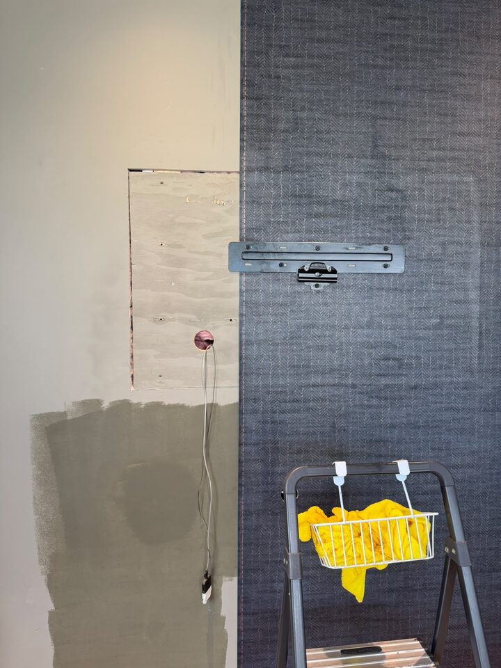Commercial wallcovering installation in progress: primed drywall beside a finished charcoal panel, Highfield, SE Calgary