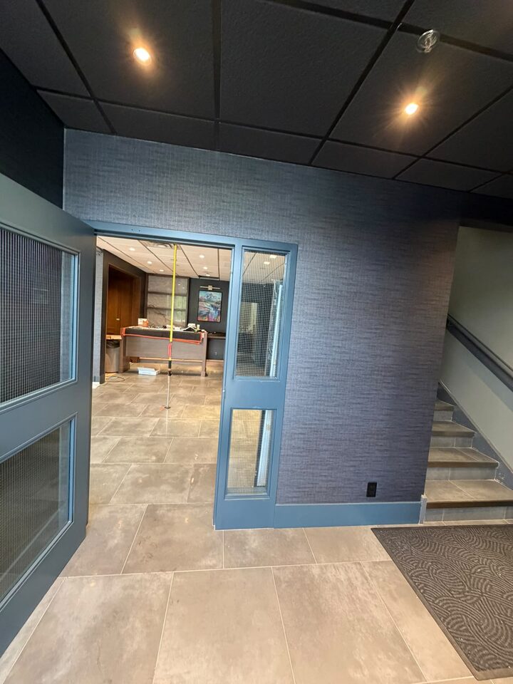 Charcoal woven-texture commercial wallcovering in an office reception lobby with stair, Highfield, SE Calgary