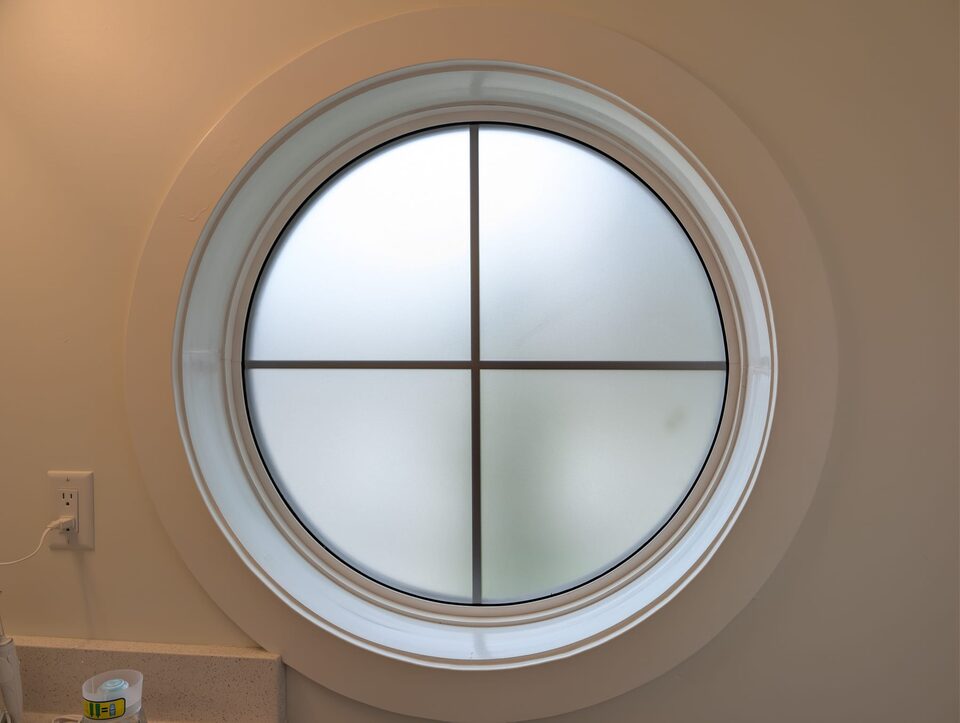 Frosted privacy film on a round bathroom window in Highland Park, NW Calgary