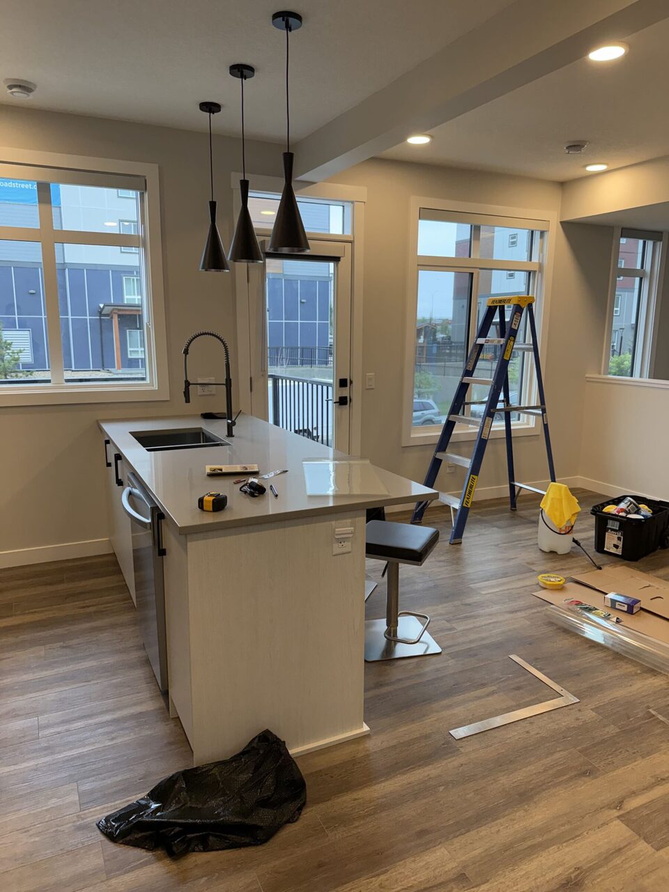Kitchen and dining-area glazing during the Livingston solar-film installation. Tools and access equipment are visible.