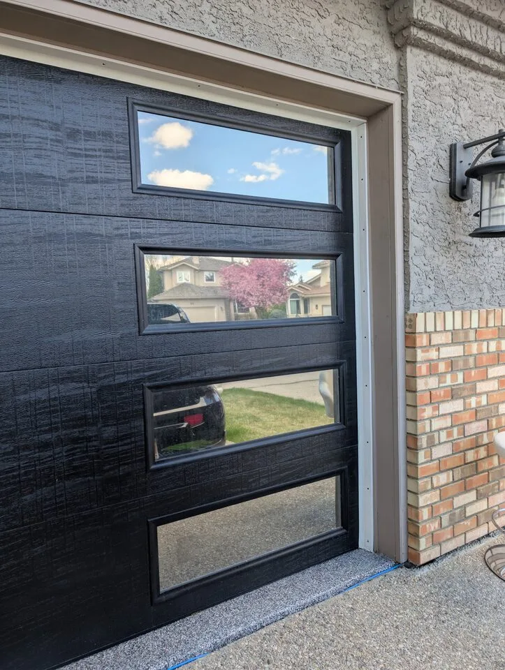Side view of reflective privacy window film on black garage door windows in McKenzie Lake Calgary