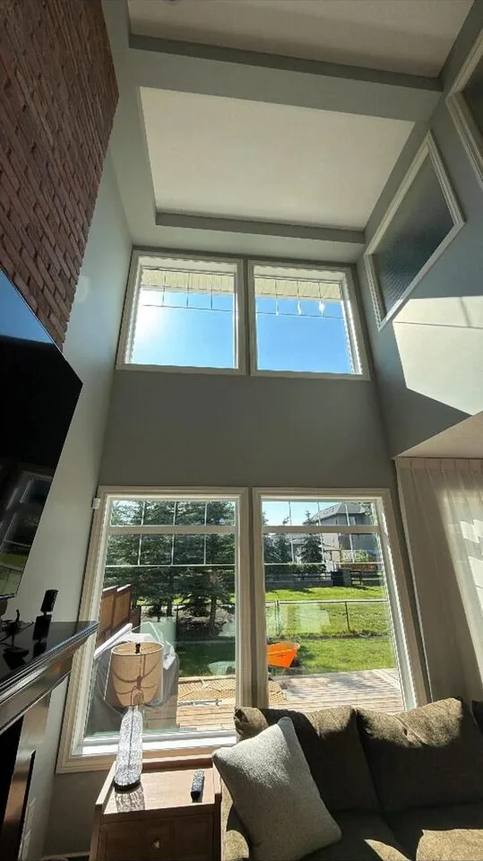 Two-storey living room with clear solar window film on tall sky-facing windows in Silverado SW Calgary