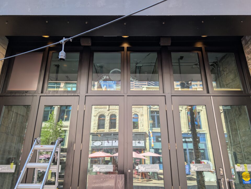 Upper storefront glazing during the commercial solar-film project on Stephen Avenue, Calgary